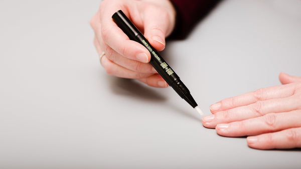 Mastic gum nail serum for natural, long fingernails being applied on fingers. 