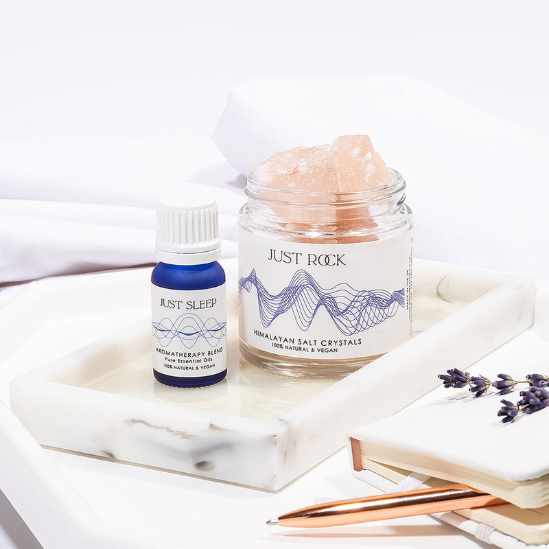 Just Sleep Gift Set - alternative to Aromatherapy Shower Steamers from Elan Skincare, a jar with Himalayan salt crystals together with essential oils blend in a blue 10 ml bottle on a table, lavender placed on a notebook,