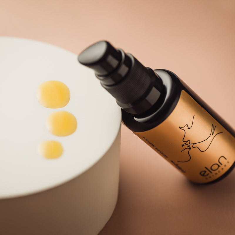 Whisper Serum from Elan Skincare showcasing three golden drops of this organic face oil.