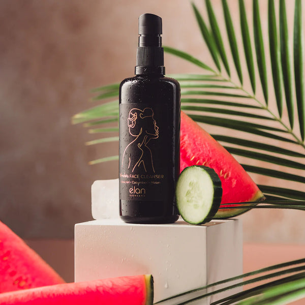 The Wonder Cleanser from Elan Skincare, deeply conditioning oil-based face cleanser that gently cleanses the skin whilst respecting skin barrier, in black, tall Miron Bottle, 100 ml, photographed with cucumber and watermelon.